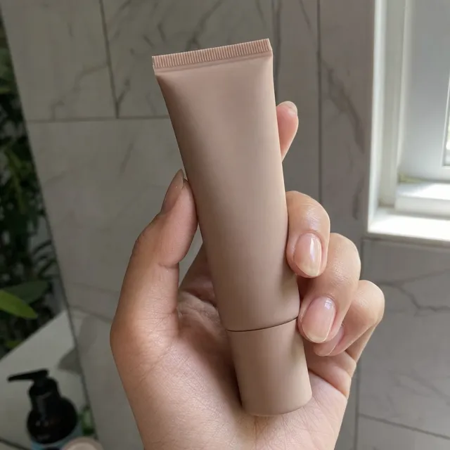 A hand holding a matte cosmetics tube in window light, shot like a creator ad