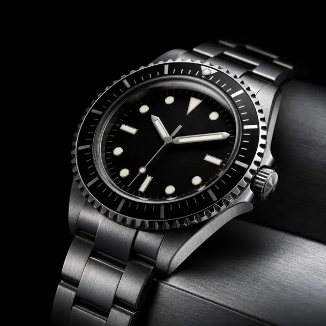 A macro of a steel dive watch under hard directional light