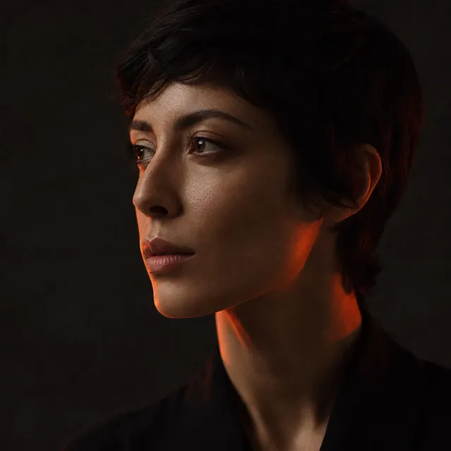 A studio portrait lit with a single warm rim light